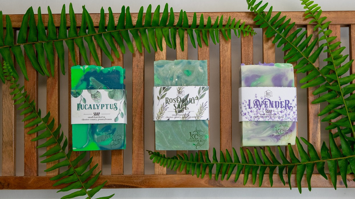 Collection of bar soaps on teak wood tray with fern leaves. Eucalyptus Rosemary Sage and Lavender Soaps