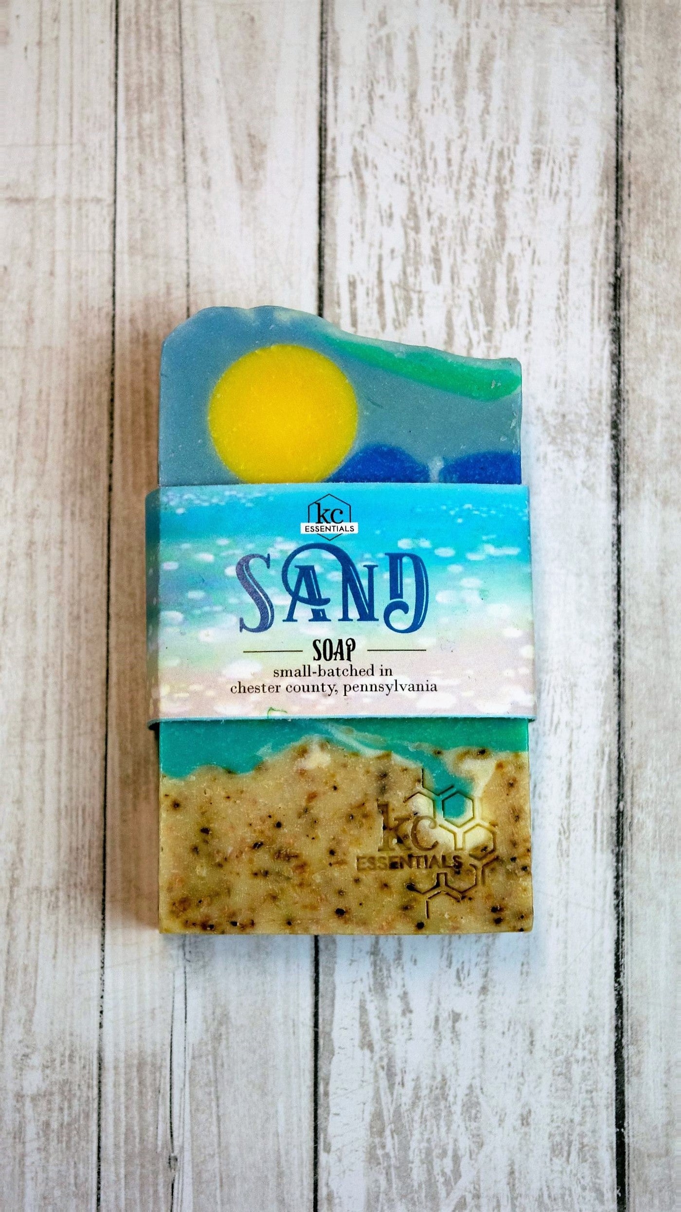 Artisan Bar Soap that shows a beach with sand surf and yellow sun high in the blue sky with wisps of clouds