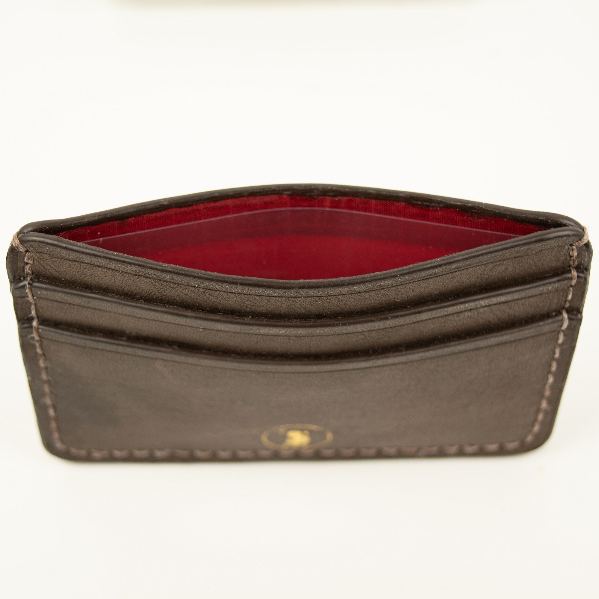 Front view of Distressed finish Chocolate brown leather slim card case with two front pockets. Center pocket is open showing a red lining and gold brand logo on front