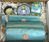 Town & Shore Handcrafted Serenity Gift set featuring T5 Leather bath kit and brush bag shown in turqouise calfskin leather. KC Essentials artisan made vegan bar soap, scented soy chakra candle in a turqoise colored metal tin with a lady in a seated yoga pose on lid, and natural solid lotion bar in metal tin. Arranged in gift box with sustainable eco-friendly white crinkle paper.