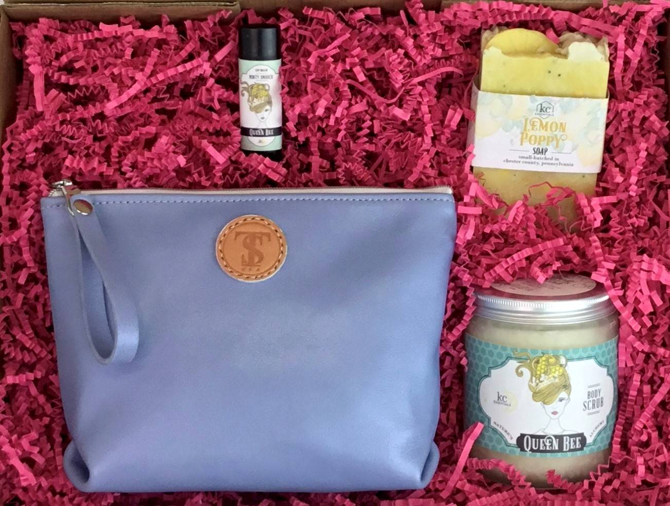 Town &amp; Shore Handcrafted Serenity Gift set featuring T5 Leather bath kit and brush bag shown in light periwinkle blue calfskin leather. KC Essentials artisan made vegan bar soap, essential oils body scrub and soothing lip balm. Arranged in gift box with sustainable eco-friendly bright pink crinkle paper.