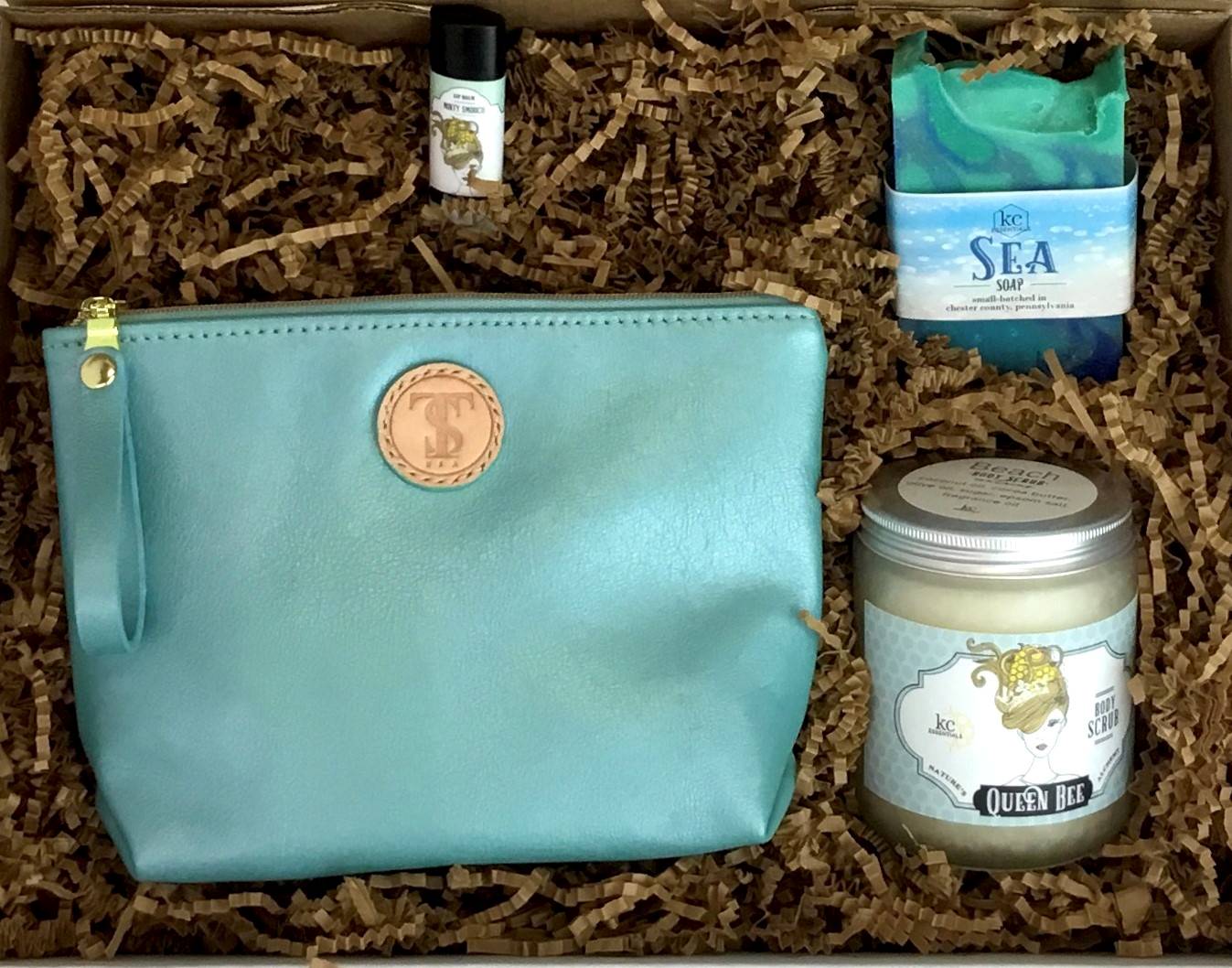 Town &amp; Shore Handcrafted Serenity Gift set featuring T5 Leather bath kit and brush bag shown in turqouise calfskin leather. KC Essentials artisan made vegan bar soap, essential oils body scrub and soothing lip balm. Arranged in gift box with sustainable eco-friendly craft crinkle paper.